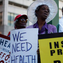 Woman holding sign saying We need Health Care