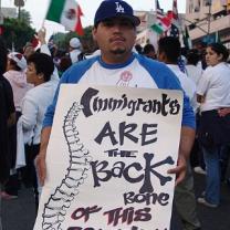 Man holding sign saying Immigrants are the Backbone of this country