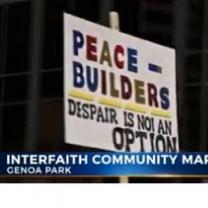 Words on a picket sign Peace Builders Despair is not an option and the banner lower third below saying Interfaith Community March, Genoa Park
