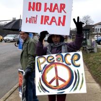 Woman holding No War with Iran and Peace protest signs