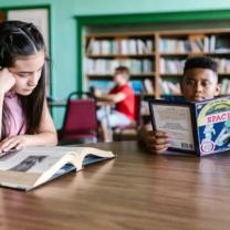 Kids reading at table in library