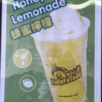 A sign with a cup with yellow liquid and words Kung Fu Tea