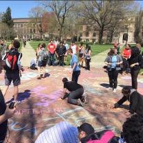 Students coloring with chalk on the Oval to cover up hate speech
