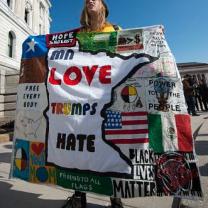 A woman protests Donald Trump with a "Love Trumps Hate" banner/blanket