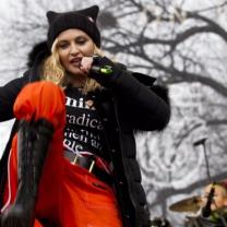 Madonna in orange pants and black bots dancing outside