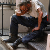 Man with head in hand in despair sitting outside on stairs
