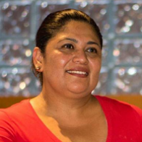 Latina woman with dark hair pulled back smiling in a red dress