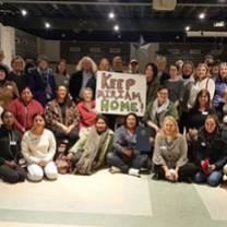 Lots of people in rows posing for the camera holding a sign that says Keep Miriam Home