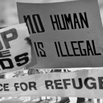 Signs at a rally one saying No Human is Illegal