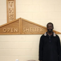 Open Shelter sign and man standing next to it