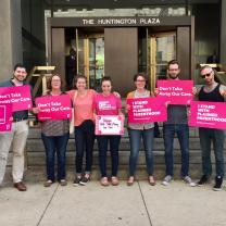 People with pink signs standing outside a government building