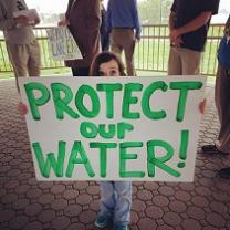 Very tiny little girl holding a sign saying Protect Our Water!