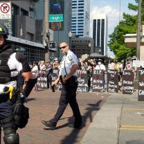 Protestors with shields as police in riot gear prepare for attack