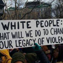 Banner saying White People What will we do to change our legacy of violence