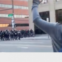 Police line and demonstrator with hands in air