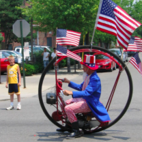 Uncle Sam in a round bike with flags in the parade