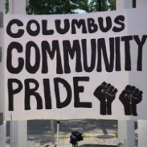 Big white outdoor sign saying Columbus Community Pride with two fist drawings