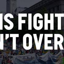 Black and white background of people at a rally and the words THIS FIGHT ISN'T OVER