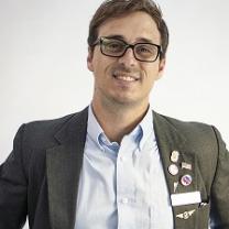 Travis Irvine in a suit and glasses
