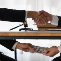 Two men shaking hands above the table and exchanging money under the table