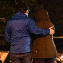 Backs of two people one hugging the other outside