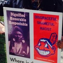 Poster with photo of Native American on left side and big cartoony smily Indian face that is Chief Wahoo the mascot of the Cleveland Indians