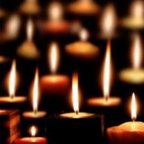 Lots of lit candles glowing in the darkness