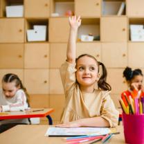 GIrl in classroom raising hand