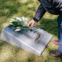Person putting flowers on a gravestone