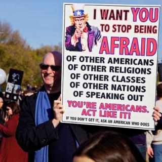 Man outside holding a sign about what Americans fear