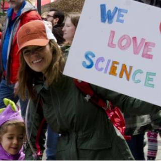 Woman with child and sign saying We Love Science