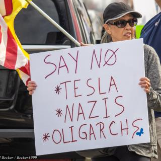 Woman holding sign at Tesla protest