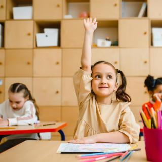 GIrl in classroom raising hand