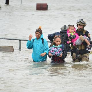 People wading through wasit deep flood