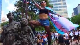Woman posing on statue wearing trans flag