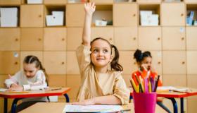 GIrl in classroom raising hand
